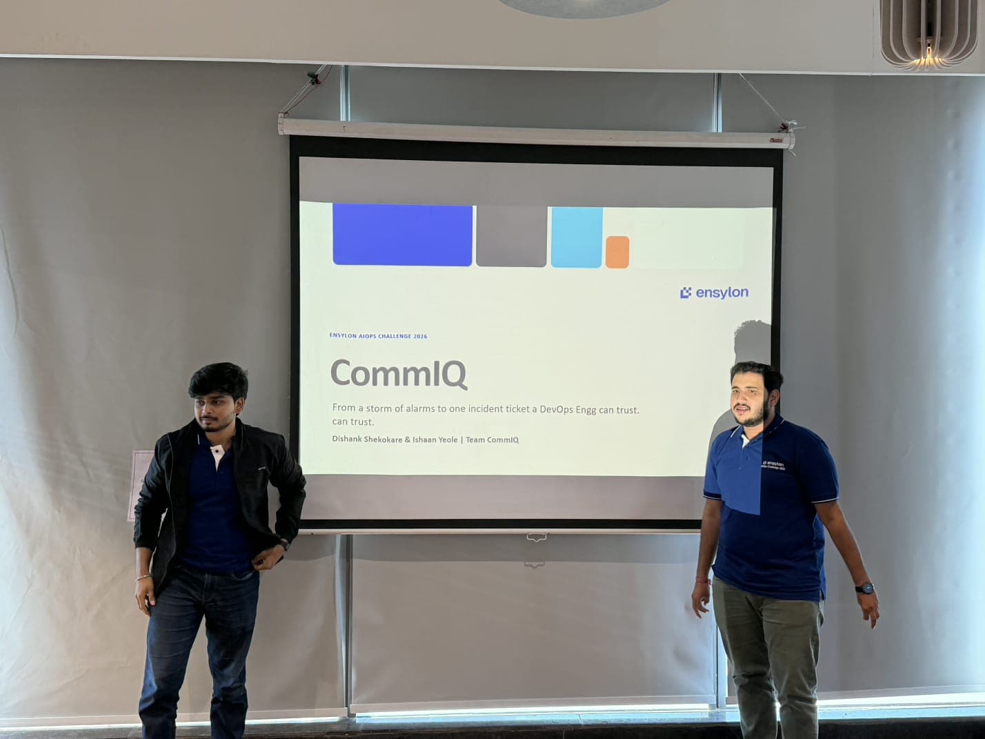 Team CommIQ presenting beside the title slide: "CommIQ — From a storm of alarms to one incident ticket a DevOps Engg can trust"
